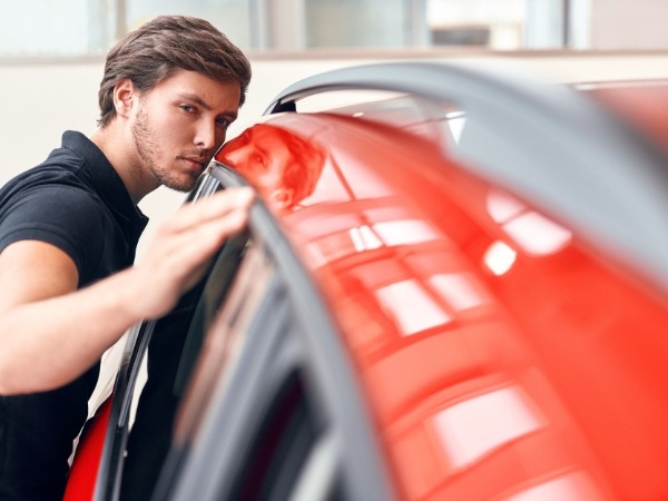 Man Inspecting a Red Car